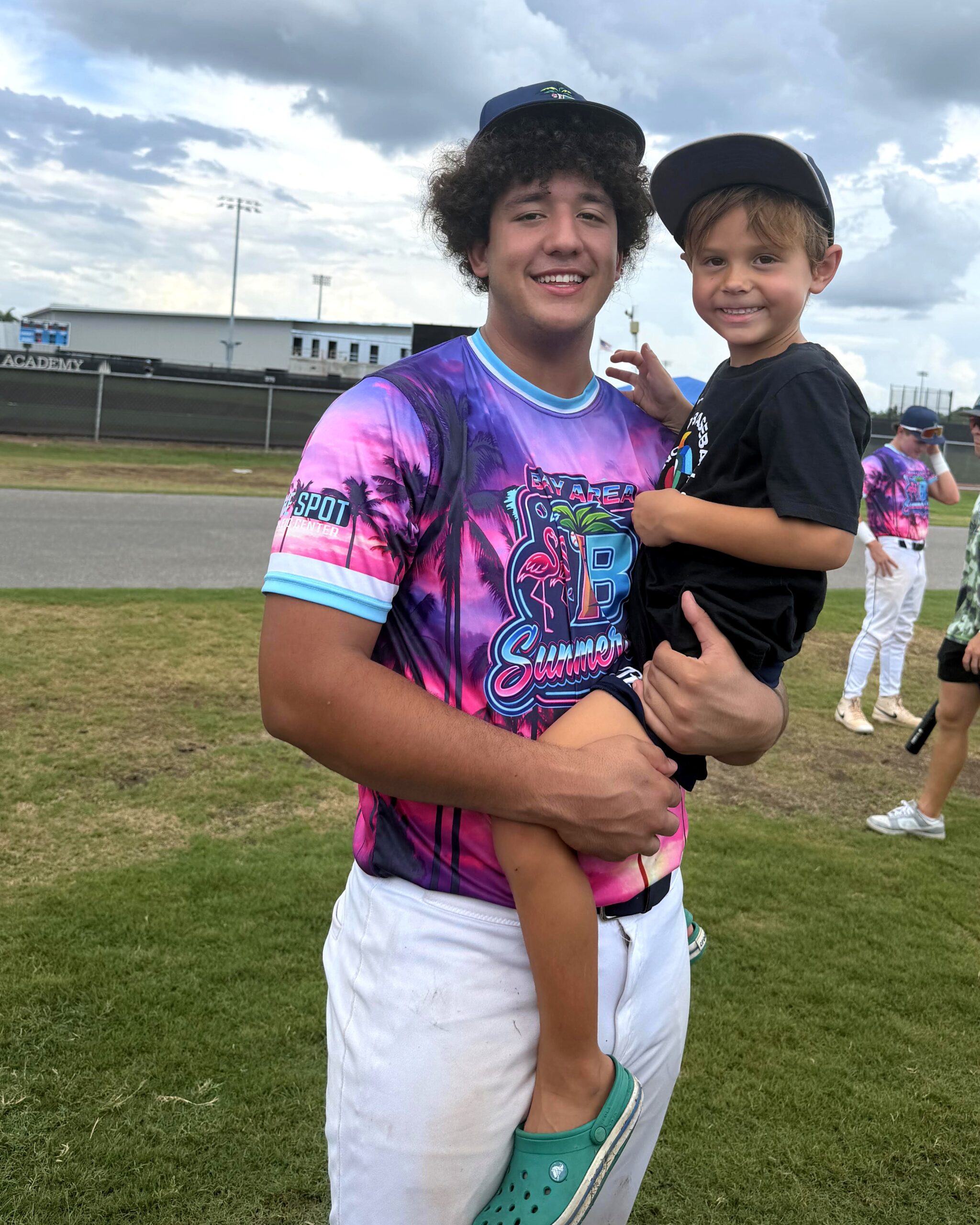 Bay Area Baseball player carrying his younger brother on the field